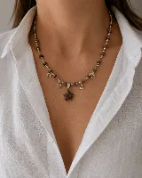 Collar de cadena de eslabones tipo bolitas plateadas, intercaladas con pequeñas piedras naturales marrones. Presenta dijes colgantes en forma de estrella de contorno plateado y un dije central de estrella de piedra natural.