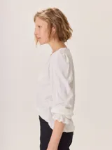 Remera de algodón con cuello en V, mangas largas con puños elásticos y volados, y estampa botánica sutil en el frente.