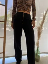 Pantalón negro de vestir, de corte recto, con bolsillos laterales y traseros. Se ajusta a la cintura con cinturón de cuero marrón.