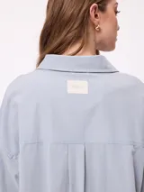 Camisa de manga larga con efecto lavado, corte oversize y cierre frontal con botones. Presenta cuello clásico y logo bordado en el pecho.