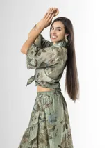 Camisa de organdí verde con estampa floral de inspiración oriental, cuello camisero, mangas cortas amplias y cierre frontal con botones.