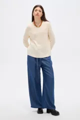 Sweater de tejido de punto fino en color blanco, con cuello redondo a la base y mangas largas de corte holgado.