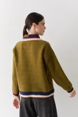 Buzo de lana tipo polo con cuello y cartera de botones en colores contrastantes. Presenta mangas con textura de ochos y puños y ruedo con terminaciones en franjas de colores.