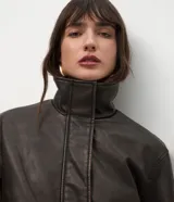 Campera de cuero sintético marrón con efecto desteñido, cuello alto y solapa de piel sintética desmontable. Cuenta con cierre frontal, bolsillos delanteros con solapa y elástico en el ruedo.