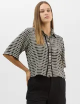 Camisa de corte holgado y silueta recta con estampado geométrico bicolor de eslabones. Presenta cuello camisero clásico, mangas cortas amplias y cierre frontal con botones y vivos a contratono.