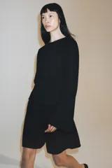Bermuda de algodón color negro, con tiro medio, cintura elástica ajustable con cordones y bolsillos laterales ocultos en costura.