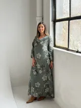 Vestido largo color verde militar con estampado floral, cuello drapeado y mangas largas de corte holgado.