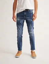 Jean azul con efecto lavado y roturas, de corte ajustado.