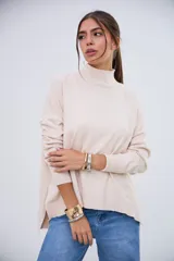 Sweater beige de cuello alto, manga larga y corte holgado con aberturas laterales en el dobladillo.