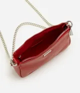 Cartera tipo baguette pequeña Satinato, confeccionada en PU color marfil, de formato alargado y estructura maleable. Cuenta con cierre superior de cremallera, placa frontal aplicada con el logo de la marca y asa de cadena doble metálica en tono plateado que permite llevarla al hombro o cruzada.