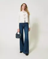 Chaqueta de hilo color crema con cuello redondo, mangas largas y cierre frontal con botones dorados. Diseño calado de crochet en la parte delantera y trasera.