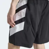 Short Adidas Adicolor Double Blocked de color negro, confeccionado en tejido ripstop. Presenta un diseño holgado, bolsillos laterales, cierre de cremallera, el logo del Trifolio bordado y detalles gráficos de franjas blancas en el lateral.