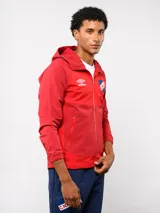 Campera deportiva Umbro del Club Nacional de Football, modelo Summit. Presenta un diseño con bloques de color en azul, rojo y blanco, con capucha, cierre frontal y bolsillos laterales con cierre. Incluye el logo de la marca y el escudo del club en el pecho.