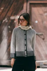 Saco reversible de tejido de punto con cuello a la base y cierre frontal de botones. Presenta un diseño de rayas verticales en dos colores, creando un efecto visual de contraste entre el interior y el exterior, con puños y ruedo en tono sólido.