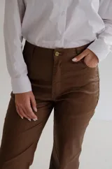 Pantalón de tiro alto con acabado engomado, de corte recto y pierna con leve apertura. Presenta cierre frontal con botón y bolsillos laterales.