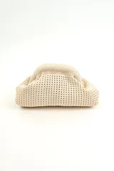 Neceser de mano color beige, con diseño tejido de punto y estructura rígida con cierre superior.