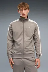 Campera Puma modelo T7 Track Jacket 692462, de color beige con franjas blancas en las mangas y cuello alto. Cuenta con cierre frontal completo y bolsillos laterales.