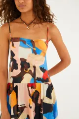 Vestido largo de algodón con estampado artístico de figuras en bloques de color, tirantes finos regulables, escote recto y falda amplia con ruedo asimétrico.