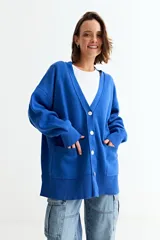 Cardigan de punto color azul, con cuello en V, cierre frontal con botones y dos bolsillos delanteros. Presenta un diseño holgado con mangas largas y puños acanalados.