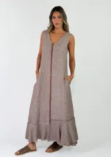 Vestido largo sin mangas, con escote en V, corte holgado y detalles de volados con flecos en el ruedo.