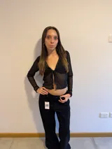 Top negro traslúcido con encaje, de mangas largas y escote en V con lazo.