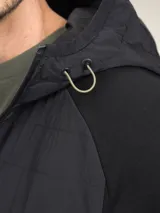 Campera verde oscuro con capucha, cierre frontal y bolsillos laterales.