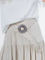 Cinto marrón trenzado con hebilla circular plateada con piedra marrón al centro.