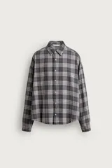 Camisa de algodón con corte boxy fit, diseño a cuadros en tonos grises y blancos, cuello clásico y manga larga con puños abotonados.