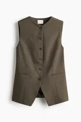 Chaleco largo de vestir color marrón oscuro, con cuello en V, cierre frontal de botones y bolsillos ribeteados. Presenta un corte entallado y abertura en la parte trasera.
