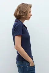 Remera de punto tipo polo color azul marino, con cuello abierto y detalles de vivo en color rojo en el borde del cuello y las mangas.