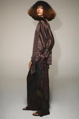 Pantalón de tiro alto confeccionado en seda, con cintura ajustable mediante cordones. Presenta un diseño de patchwork con diversos estampados geométricos y paisley en tonos tierra, verde y violeta.