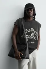 Camiseta sin mangas (tank top) de algodón con efecto lavado oscuro, corte cropped y cuello redondo. Presenta un estampado frontal en blanco con varios caballos en estilo gótico y texto en la parte inferior.