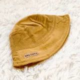 Gorro tipo bucket de pana color mostaza, con etiqueta de la marca Valente en el frente.