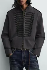 Chaqueta cropped de algodón con cuello mao y manga larga. Presenta un diseño de inspiración militar con alamares decorativos en contraste en el frente, trabillas en los hombros y cierre frontal con ganchos metálicos.