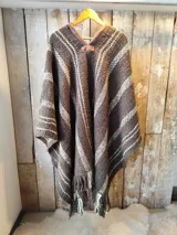 Poncho de lana tejido en telar con diseño a rayas y flecos en el ruedo, con detalle de cuero en el cuello.