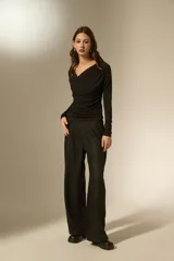 Top de manga larga color negro, con cuello en V y diseño drapeado en el frente. Confeccionado en tejido ajustado al cuerpo.