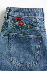 Short de denim de algodón rígido, color azul claro, con cinco bolsillos y diseños florales bordados en la parte delantera. Modelo de tiro alto con cierre de botón.
