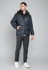 Campera puffer verde militar con capucha negra de cuero sintético, cierre frontal con cremallera y bolsillos laterales con cierre.