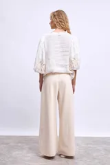 Blusa blanca de lino con cuello mao, mangas 3/4 abullonadas con apliques bordados en forma de hojas y cierre frontal con botones.