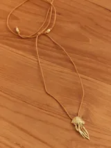 Collar con dije de medusa en metal dorado y cordón de hilo color tostado ajustable.