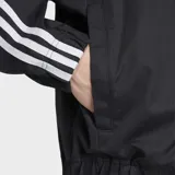 Campera deportiva Adidas modelo SST Adicolor Classics Cotton Twill, color negro con las clásicas tres tiras blancas en las mangas y el logo del Trifolio bordado en el pecho. Cuenta con cierre frontal y bolsillos.