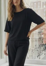 Blusa negra de corte oversize, con cuello redondo y mangas cortas holgadas. Confeccionada en tejido ligero de poliéster con spandex.