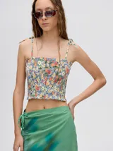 Top crop de tela denim con efecto fruncido, breteles finos ajustables con lazos y diseño entallado al cuerpo.