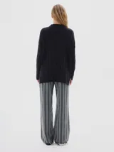 Buzo tejido de punto color beige, con cuello subido, diseño oversized y aberturas laterales en el ruedo.