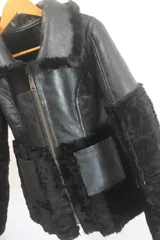 Gamulán reversible de cuero genuino color marrón oscuro con interior de piel sintética en tono crema. Presenta cuello solapa, cierre frontal con cremallera y mangas largas con puños de piel.