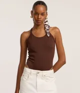 Body marrón oscuro de tejido acanalado, con escote redondo y breteles finos que se cruzan en la espalda.