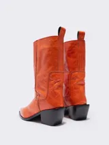 Botines cowboy de piel color naranja, con tacón en punta y tirador en la parte trasera. Forro de piel con plantilla con logo a contraste y suela con logo.