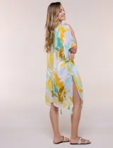 Kimono de gasa ligera con estampado floral en tonos amarillos, celestes, blancos y marrones, de manga corta amplia y diseño abierto con detalle de borlas en el ruedo asimétrico.
