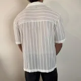 Camisa de manga corta confeccionada en tejido de crochet con diseño de rayas verticales, cuello solapa y cierre frontal con botones.