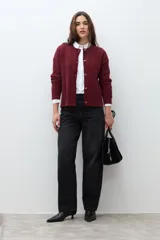 Cardigan bordó de manga larga con cuello redondo y cierre frontal de botones. Presenta un tejido con patrón de estructuras.